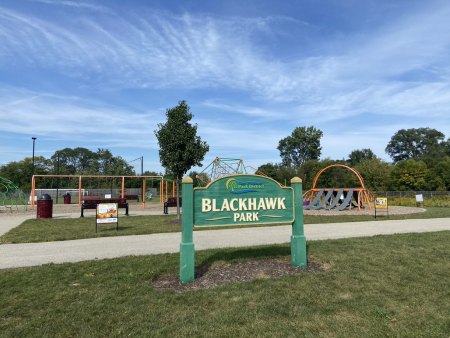 Blackhawk Park sign with the StoryWalk signs behind it on a sunny day. 